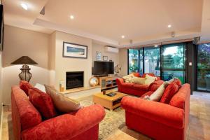 a living room with two red couches and a tv at Sea Vista - Beachside Resort-style Bliss in Broadwater