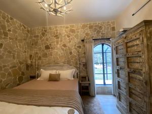 a bedroom with a bed and a stone wall at Cold Stone Villa -a cozy escape above the clouds in Kodaikānāl