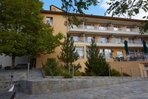 a large yellow building with trees in front of it at Хотел "Божур" in Mineralni Bani