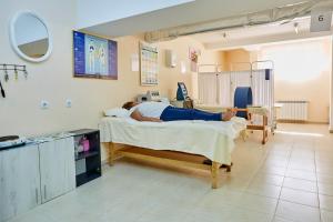 a woman laying on a bed in a hospital room at Хотел "Божур" in Mineralni Bani
