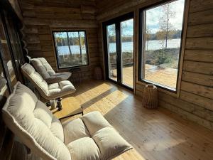 a living room with couches and windows in a log cabin at Arctic Private Island - All inclusive HB and activities in Rovaniemi
