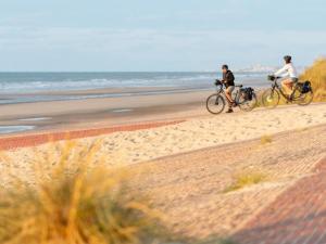 two people riding bikes on the beach at Studio Villa Leone à Deux Pas de la Mer in Dunkerque