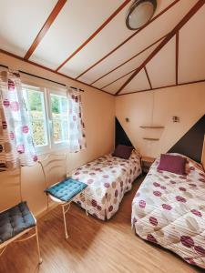 una camera da letto con due letti e una sedia di Chalet Du Bonheur Lac De Guerledan a Caurel