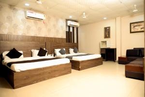 a bedroom with two beds and a television in it at Hotel De Agya Paradise in Ludhiana +15 photos