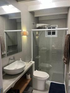 a bathroom with a sink and a toilet and a shower at Casinhas do Peró Refúgio com Jardim e WiFi Rápido in Cabo Frio