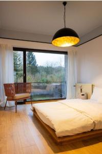 una camera da letto con un letto e una grande finestra di Maison modernisée au caractère 70ies a Herstal
