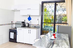 a kitchen with white cabinets and a glass window at Modern pool house in Kampala in Kampala
