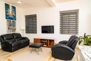 a living room with two leather chairs and a tv at Modern pool house in Kampala in Kampala