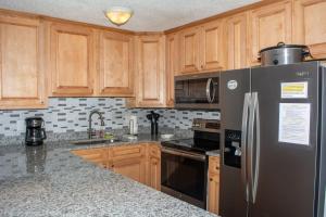 a kitchen with wooden cabinets and a stainless steel refrigerator at Winterplace Condo Ski in Ski out E103 in Ghent