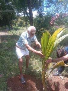 ein älterer Mann berührt eine Bananenpflanze in der Unterkunft Sai Arunachala Farmstay in Tiruvannāmalai