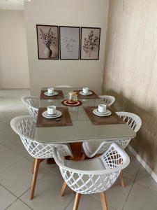 einen Tisch und Stühle mit Tassen und Tellern darauf in der Unterkunft Apto 2 suítes em Aracajú a 300 metros da Orla in Aracaju
