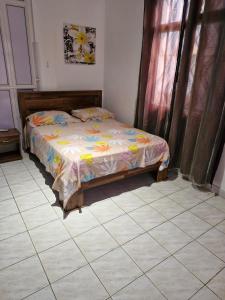 a bed in a room with a tiled floor at VBM Carangues in Blue Bay +2 photos