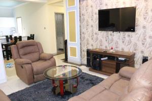 a living room with two chairs and a flat screen tv at elegant luxury three bedroom apartment with swimming pool fully equipped gym children playing ground ample parking space and a relaxing rooftop with breathtaking scenic views in Nairobi
