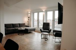 a living room with a couch and chairs and windows at EmsQuartier in Norderney