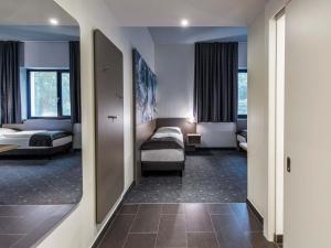 a hotel room with two beds and a mirror at B&B Hotel München-Olympiapark in Munich