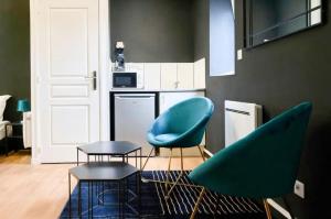 a living room with two chairs and a table and a kitchen at Suite Balnéo Privée Design Calme Proche Lille in Roubaix +15 photos