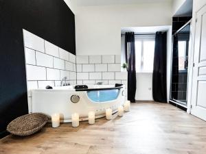 a bath tub in a bathroom with black and white tiles at Suite Balnéo Privée Design Calme Proche Lille in Roubaix