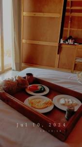 a tray with two plates of food on a bed at Mishmish wood house in Nuweiba