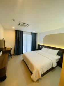 a bedroom with a large white bed and a desk at Lumia Hotel in Ho Chi Minh City