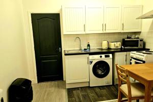 a kitchen with a black door and a washing machine at Flat - Sleeps 4 - WiFi in Bridgend +3 photos