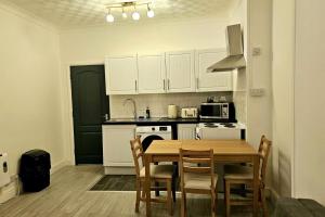 a kitchen with a table and chairs and a kitchen with white cabinets at Flat - Sleeps 4 - WiFi in Bridgend