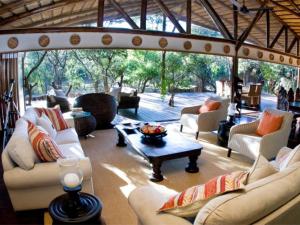 un soggiorno con divani bianchi e tavolo di Ihlozi Bush Lodge a Hluhluwe