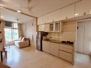 a kitchen with white cabinets and a refrigerator at Thane's First Hidden door studio - Hiranandani Estate in Thane
