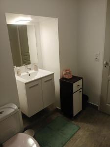 a bathroom with a sink and a toilet and a mirror at La petite maison in Gourdon-en-quercy