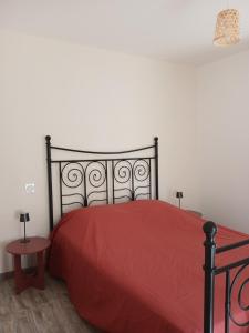 a bedroom with a red bed with a red comforter at La petite maison in Gourdon-en-quercy