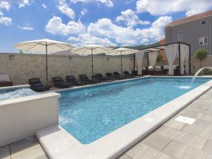 a swimming pool with chairs and umbrellas on a building at Grebastica Poolside Villa in Grebaštica