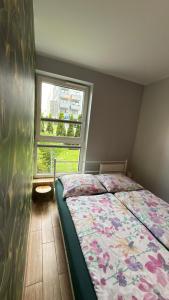 a bedroom with a bed with a floral comforter and a window at 2 Tyskie Apartamenty z ogródkiem in Tychy