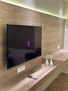 a flat screen tv on a wall with two vases at Easy Stayz - Premium stays in Greater Noida in Greater Noida