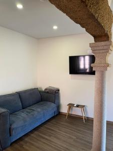 a living room with a blue couch and a tv at Casa da Saboaria in Almeida