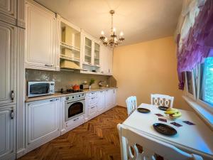 ヴァルナ・シティにあるThe Trinity Residenceの白いキャビネットとテーブルと椅子のあるキッチン