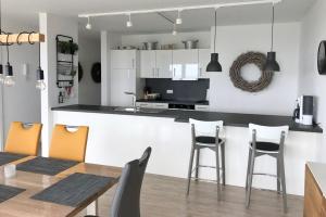 eine Küche und ein Esszimmer mit einer Theke und Stühlen in der Unterkunft NordseeResort Friesland Ferienhäuser NordseeResort Friesland 48-6-n in Schillig