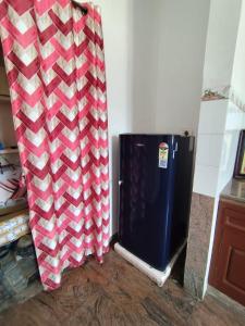 a black refrigerator in a room with a red and white curtain at La Coromandel Luxury in Puducherry
