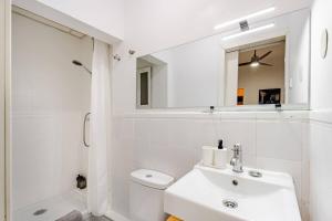 a white bathroom with a sink and a mirror at Apartamento con encanto en Malasaña in Madrid +30 photos