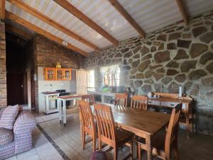 a kitchen with a wooden table and a stone wall at Treeferns Trout Lodge in Dullstroom