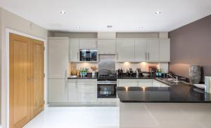 Una cocina con gabinetes blancos y una encimera negra. en Native Waterloo, en Londres