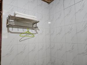 にあるBugoma Palms Resort Sand Beachのタオル掛けとタオルを備えた白いタイル張りのバスルーム +114枚の写真