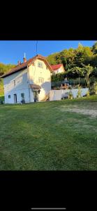 a large white house with a grass field in front of it at Vikendica Amaro in Kiseljak