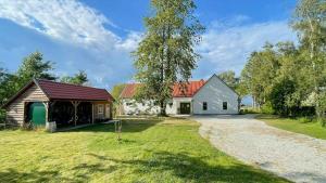 eine Scheune und ein weißes Haus mit einer Auffahrt in der Unterkunft Stone House With Sea View In Katthammarsvik in Katthammarsvik