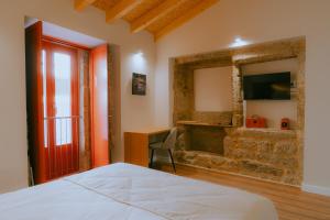 a bedroom with a bed and a desk and a television at Hotel Recanto do Avia in Ribadavia