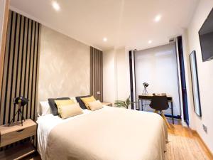 a bedroom with a large white bed and a desk at Suite Centro By Silastur in Gijón