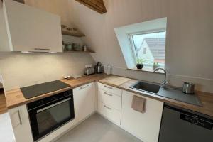 a kitchen with white cabinets and a sink and a window at La Girouette in the heart of a farmhouse in Mittelhausbergen