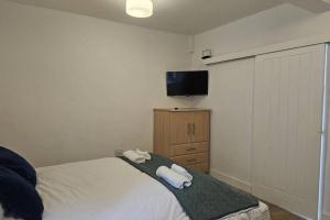 a bedroom with a bed and a flat screen tv at Studio - Sleeps 2 - Parking - WiFi in Bridgend