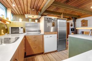 a kitchen with stainless steel appliances and wooden cabinets at Sdr Strandvej 10, A Central Holiday Oasis in Løkken