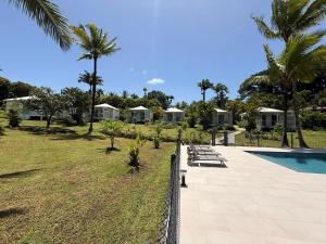 a resort with a swimming pool and palm trees at Domaine de la Glacière in Petit-Bourg