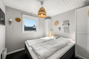 a bedroom with a large white bed with a window at Rent A Cozy Holiday Home At Pirupshvarrevej 5A! in Blokhus
