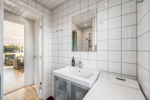 a white bathroom with a sink and a mirror at Rent A Cozy Holiday Home At Pirupshvarrevej 5A! in Blokhus +24 photos